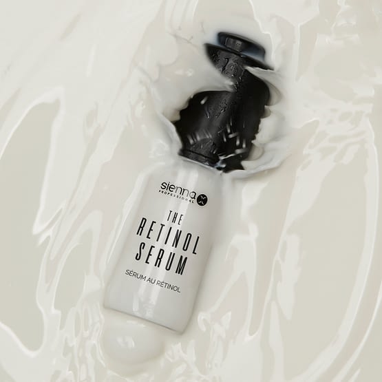 the retinol serum by sienna x. The image shows the product bottle slightly submerged in liquid.